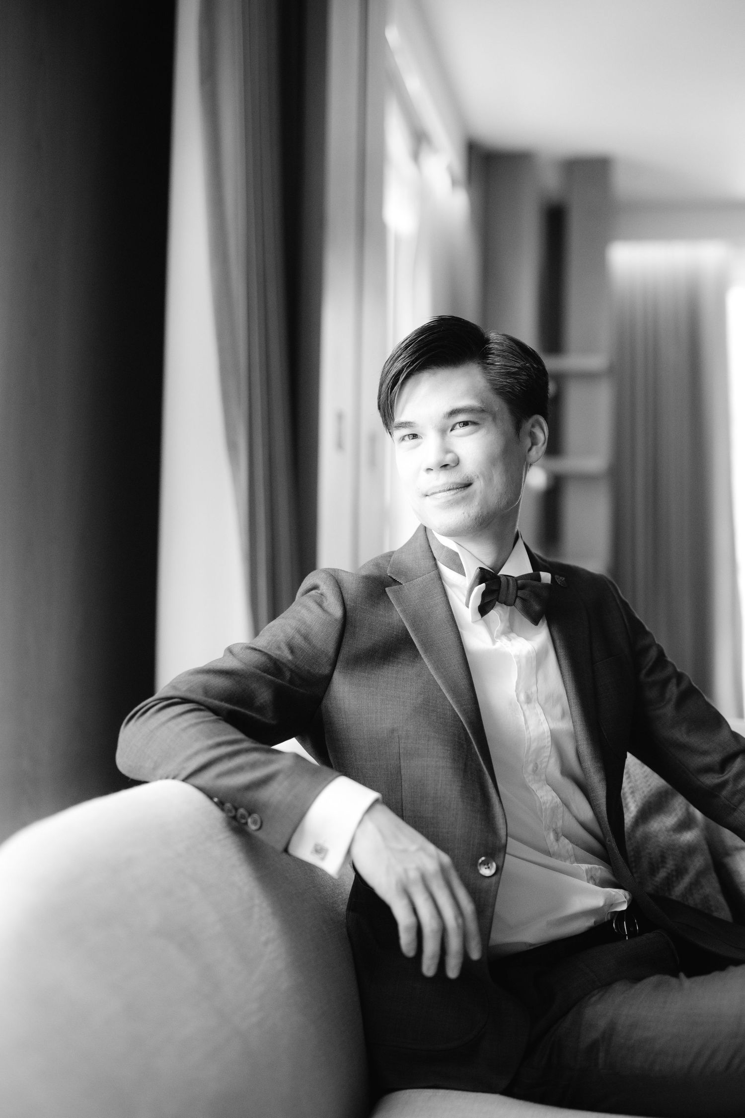 Black and white portrait series showing elegant suit-clad figure in various seated poses against bright window light.