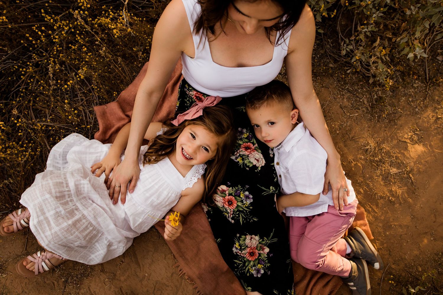 Photo of children looking at the camera while laying in their moms lap for a mom and me portrait session.