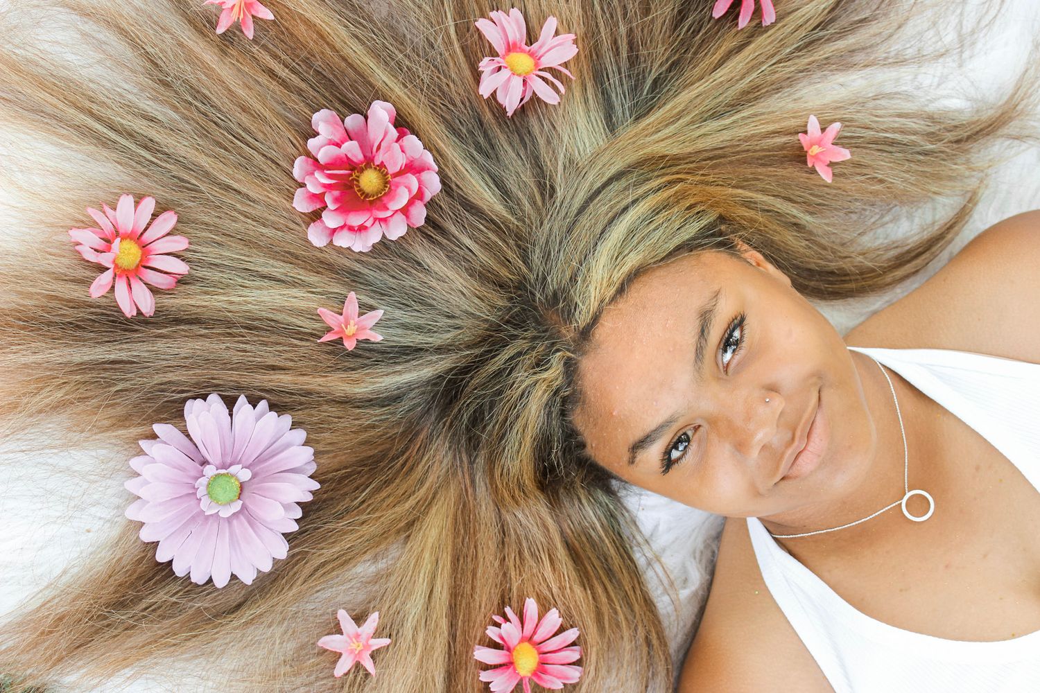 Pink daisies arranged in blonde hair creating a floral crown effect.