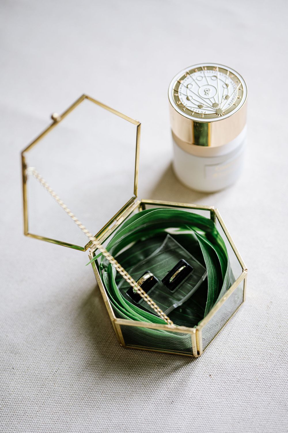 Gold hexagonal jewelry box with green velvet interior and decorative cream container.