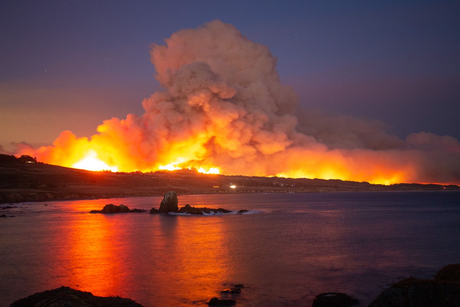 Massive wildfire creates orange glow and smoke plume at sunset over coastal waters. CZU fire, Pigeon Point, San Mateo Coast, California
