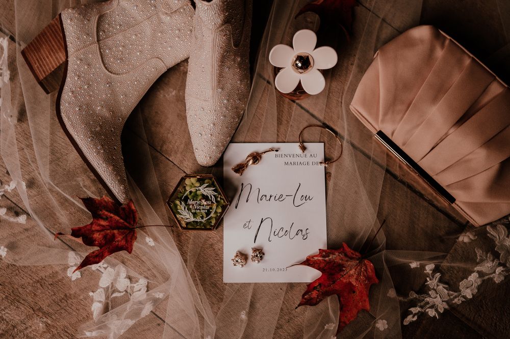 Vintage-style wedding invitation styled with autumn maple leaves and dried flowers in sepia tones.