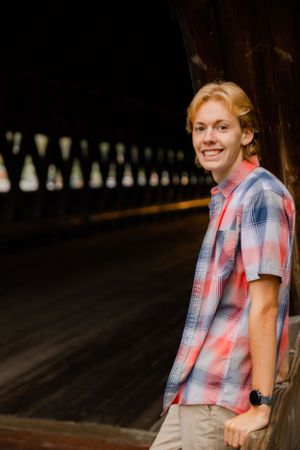 Portrait sequence in wooden covered area wearing casual plaid shirt outfit.