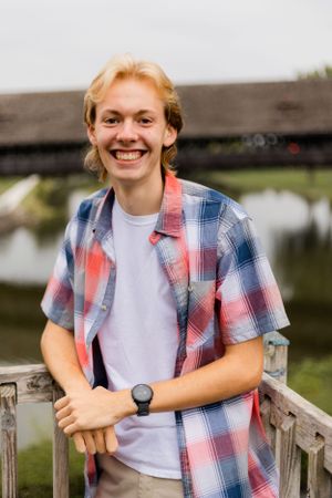 Casual portraits on wooden bridge wearing plaid shirt and white t-shirt combination.