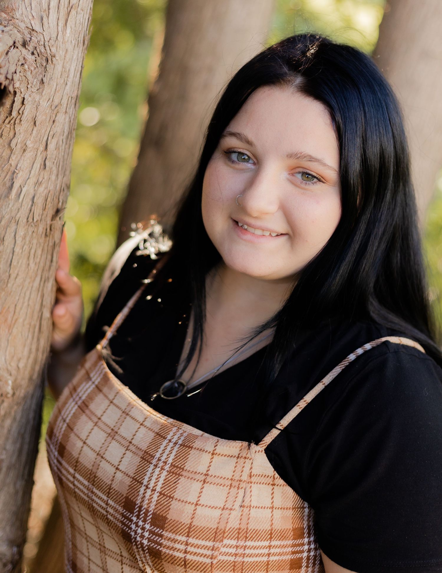 Portrait series against natural wood backdrop wearing plaid and dark clothing.