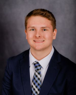 Professional portrait in business attire against dark background.