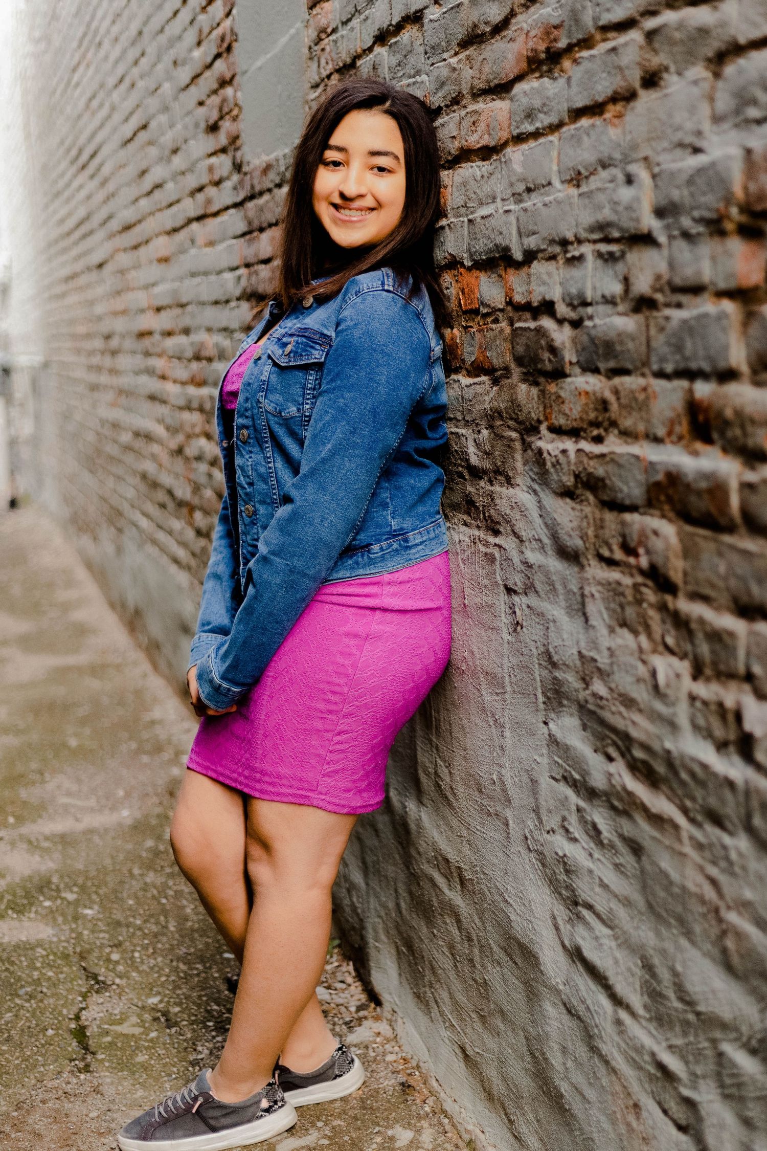 Casual fashion photography in an industrial setting with brick wall backdrop.