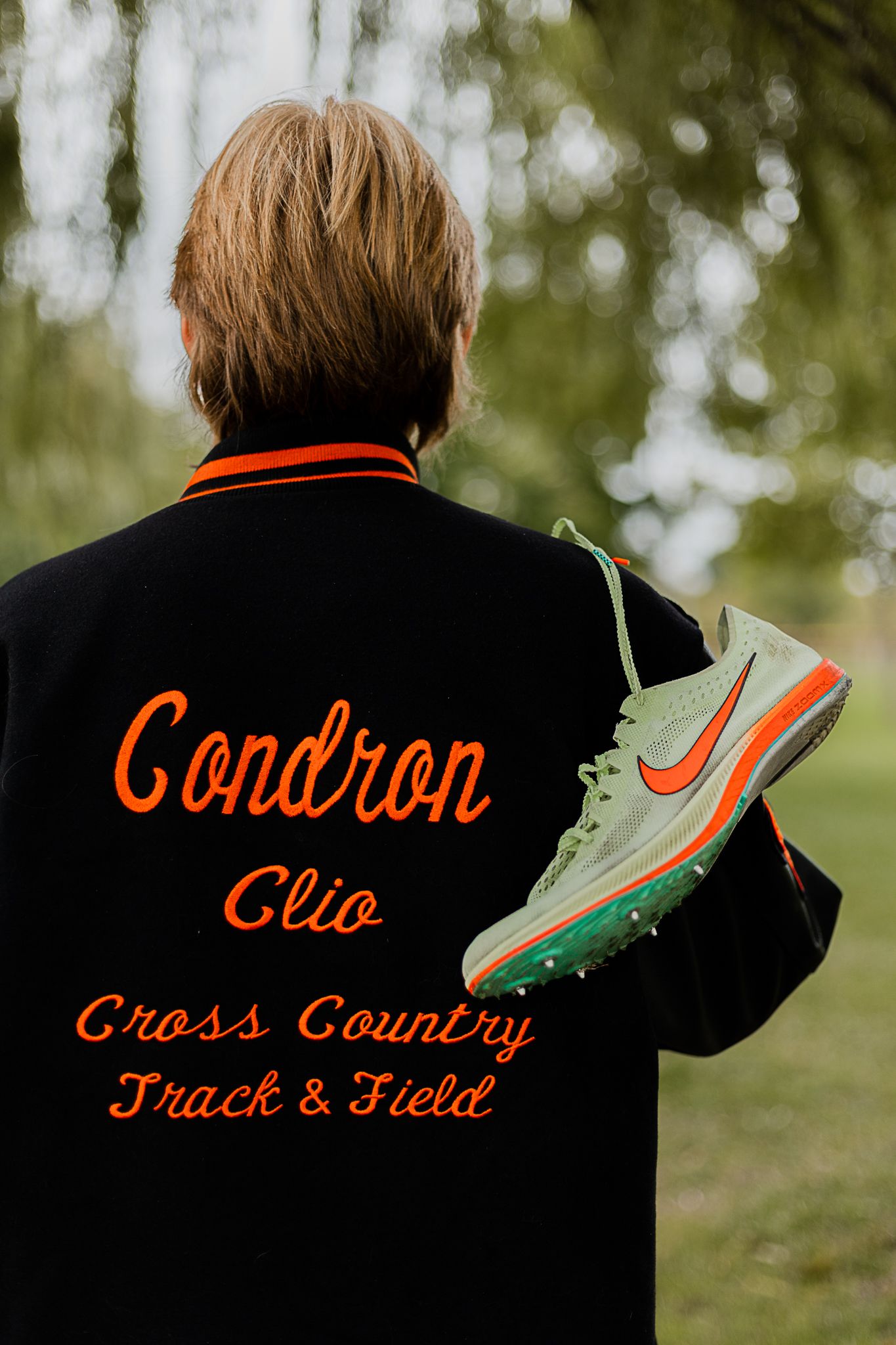 Orange lettering on black clothing showing 'Cross Country Track & Field' text.