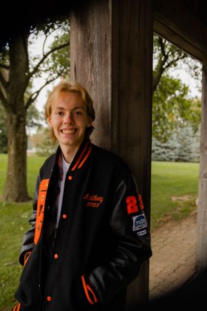 Portrait series featuring black and orange varsity jacket in wooden covered area.