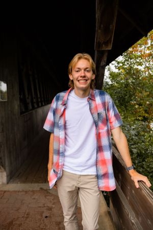 Casual portraits in covered walkway wearing plaid shirt and white t-shirt.