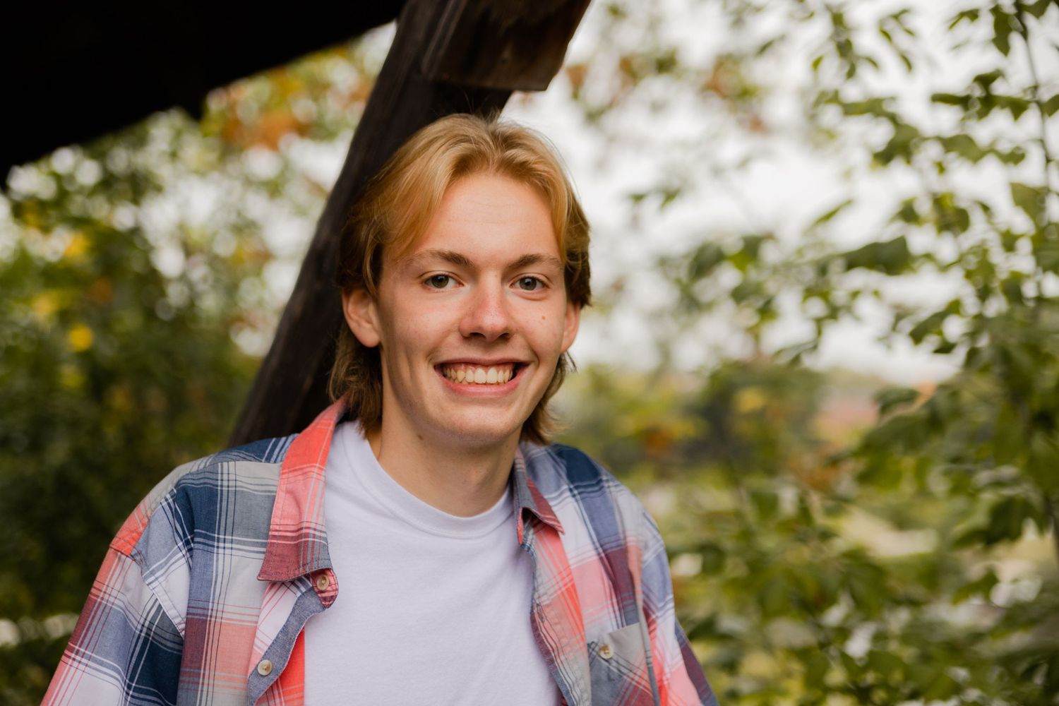 Outdoor portrait series featuring red and blue plaid shirt in natural setting.