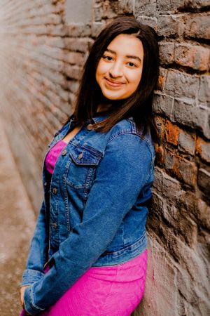 Creative portrait against textured brick walls combining denim and bright pink fashion.