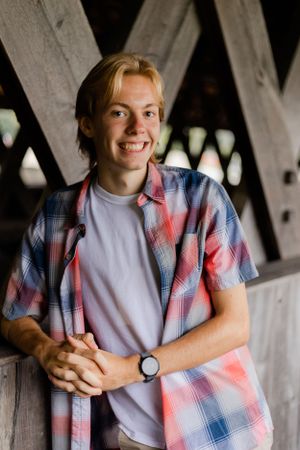 Indoor portraits showing red and blue plaid shirt against wooden structural background.