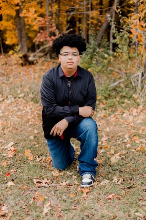 Relaxed poses on ground covered with autumn leaves in wooded setting.