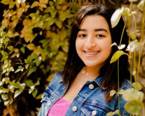 Outdoor portrait with autumn foliage featuring a denim jacket and pink dress combination.