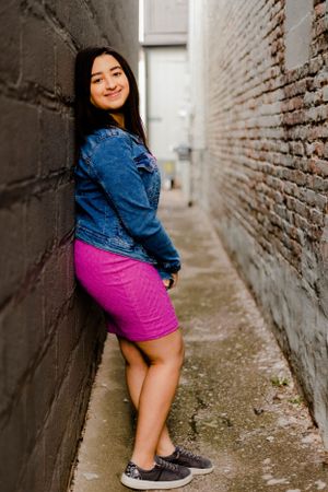 Urban photoshoot in a narrow brick alleyway showcasing casual street style.