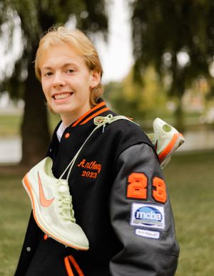 Athletic wear photoshoot featuring black and orange varsity jacket with mint green sneakers.