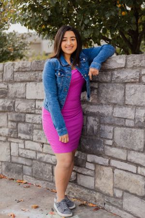 Outdoor fashion photography with stone wall and autumn leaves in background.