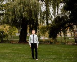 Wide landscape shots of someone walking under weeping willow trees in a park.
