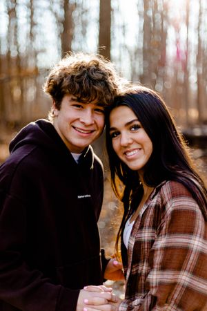 Couple in casual wear sharing a moment in autumn forest setting.
