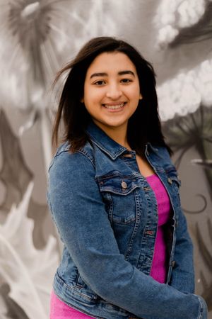A stylish outfit featuring a denim jacket and bright pink dress against a gray background.
