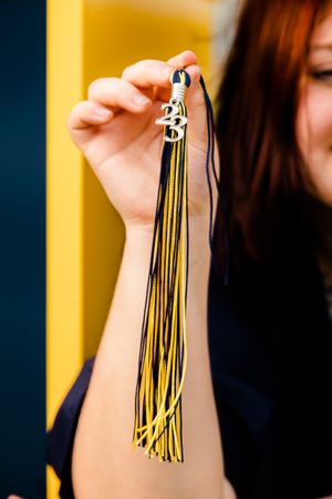 Close-up shots of blue and gold graduation tassel against dark background.