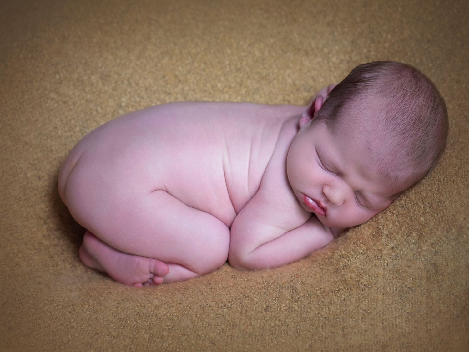 newborn baby boy in the nude laying on a yellow blanket sleeping
