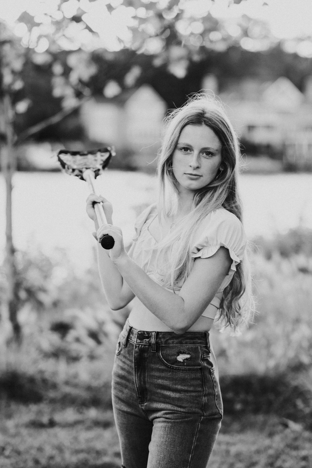 Black and white portrait holding trophy in casual attire outdoors.