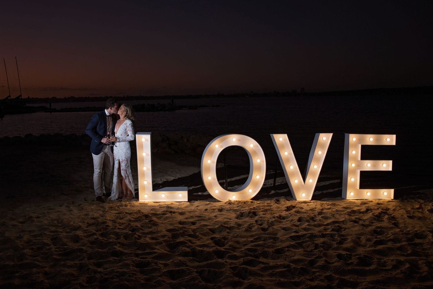 bride and groom at night kissing next to love letters