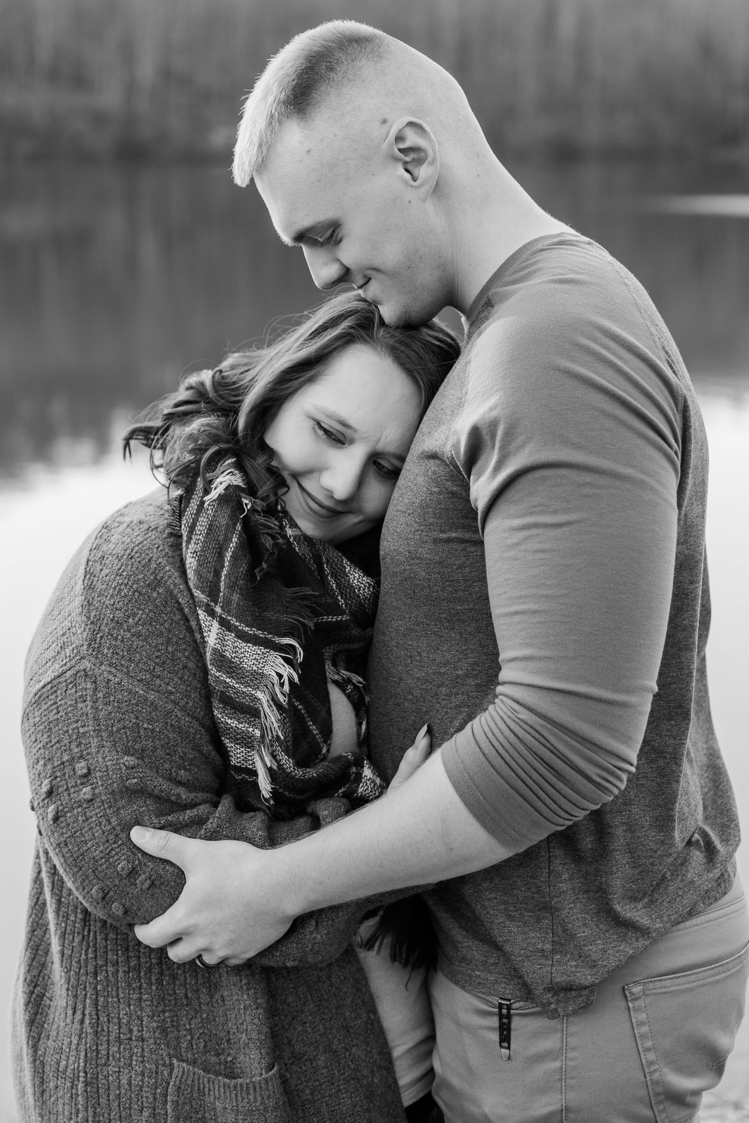 Black and white photo series showing an intimate embrace between a couple near a lake.