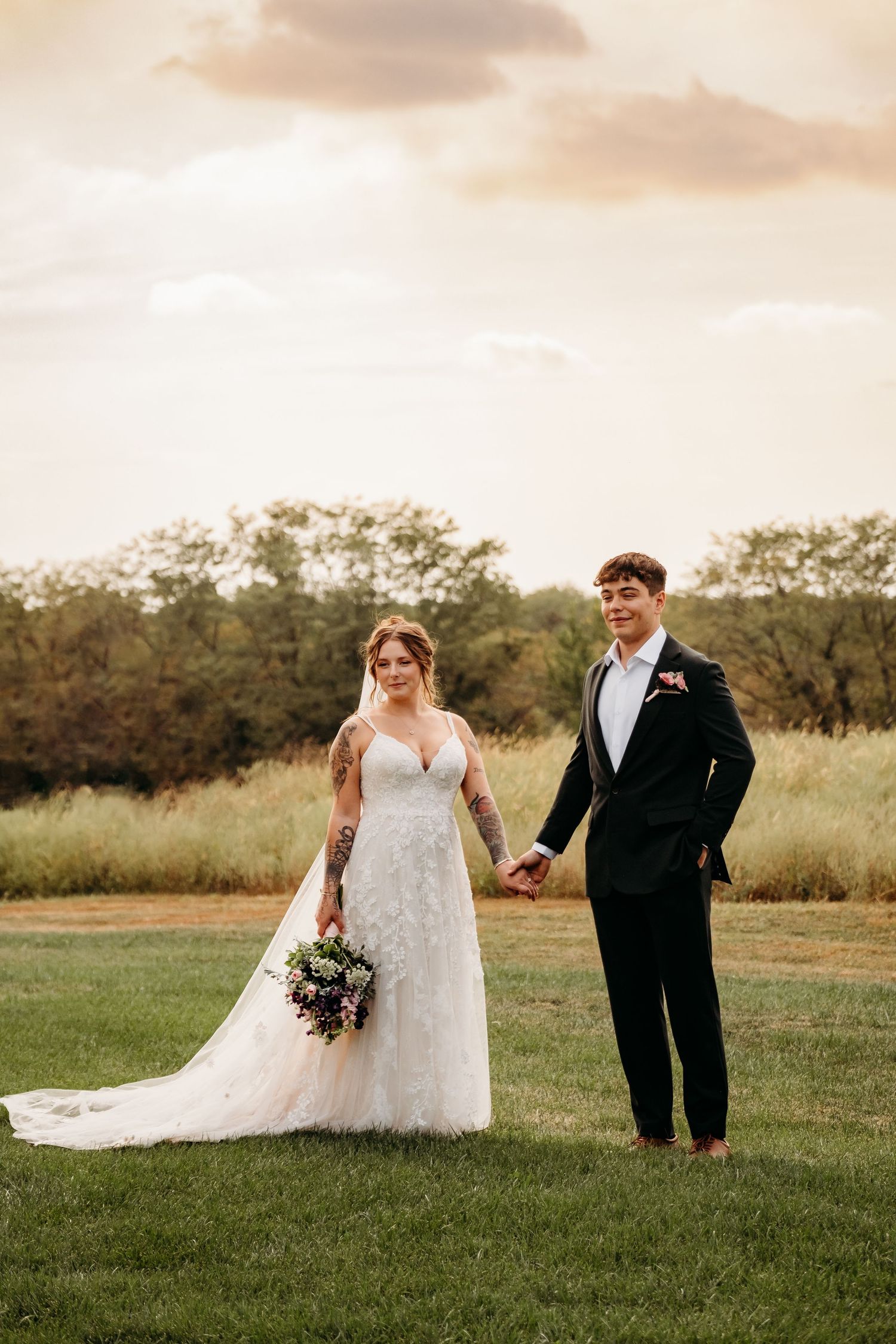 Couple stands together in wedding attire in front of a field during elopement in Colorado.