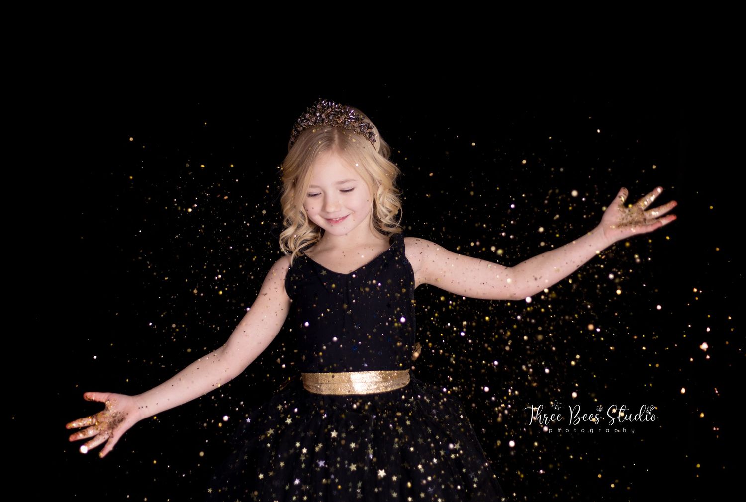 A black dress with gold belt twirls against a starry dark background.