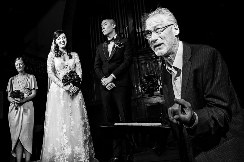 Black and white candid wedding ceremony moment showing interactions between members of the wedding party.
