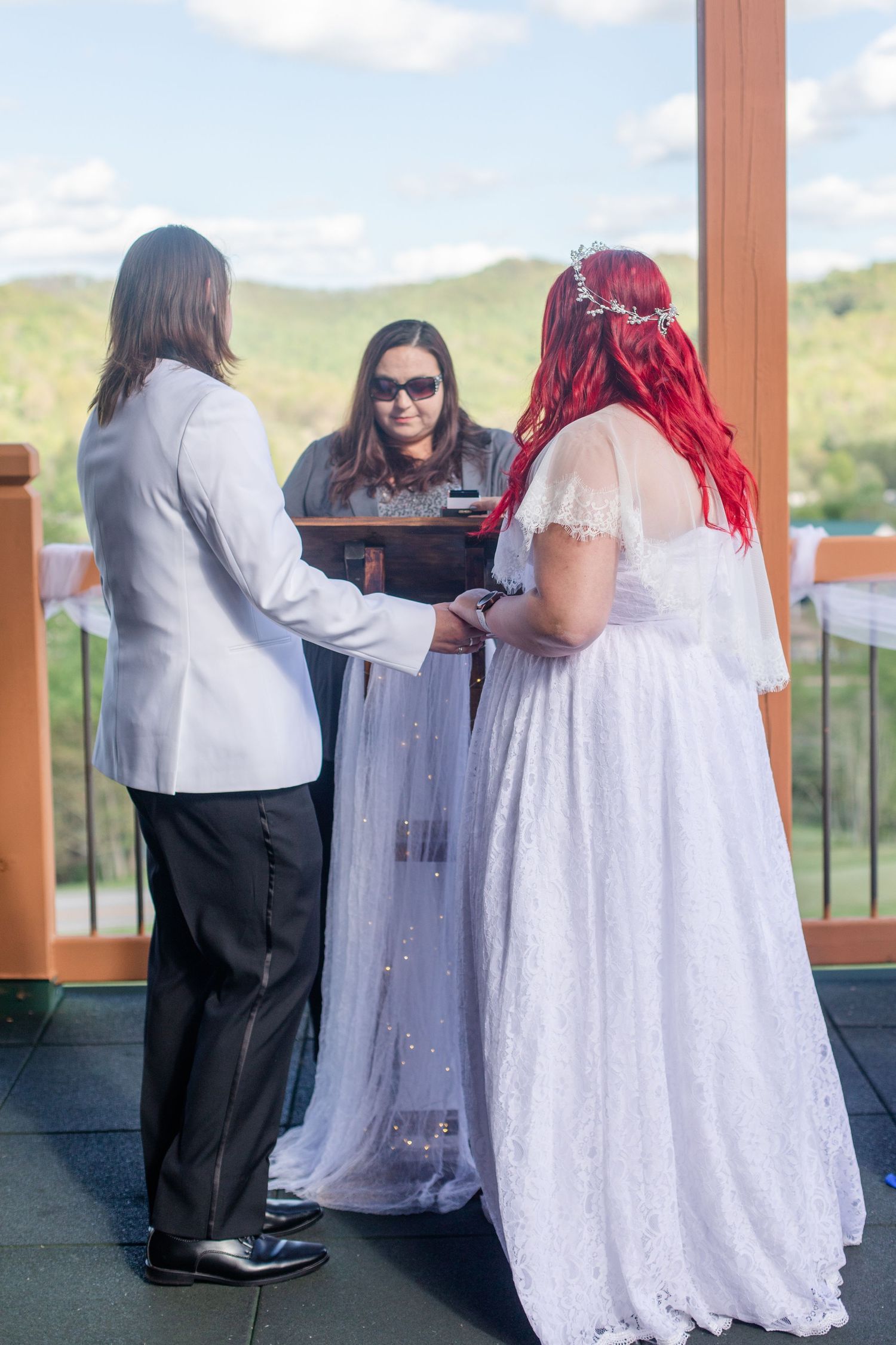 Wedding party gathers on a scenic deck during a celebration with mountains in the background.
