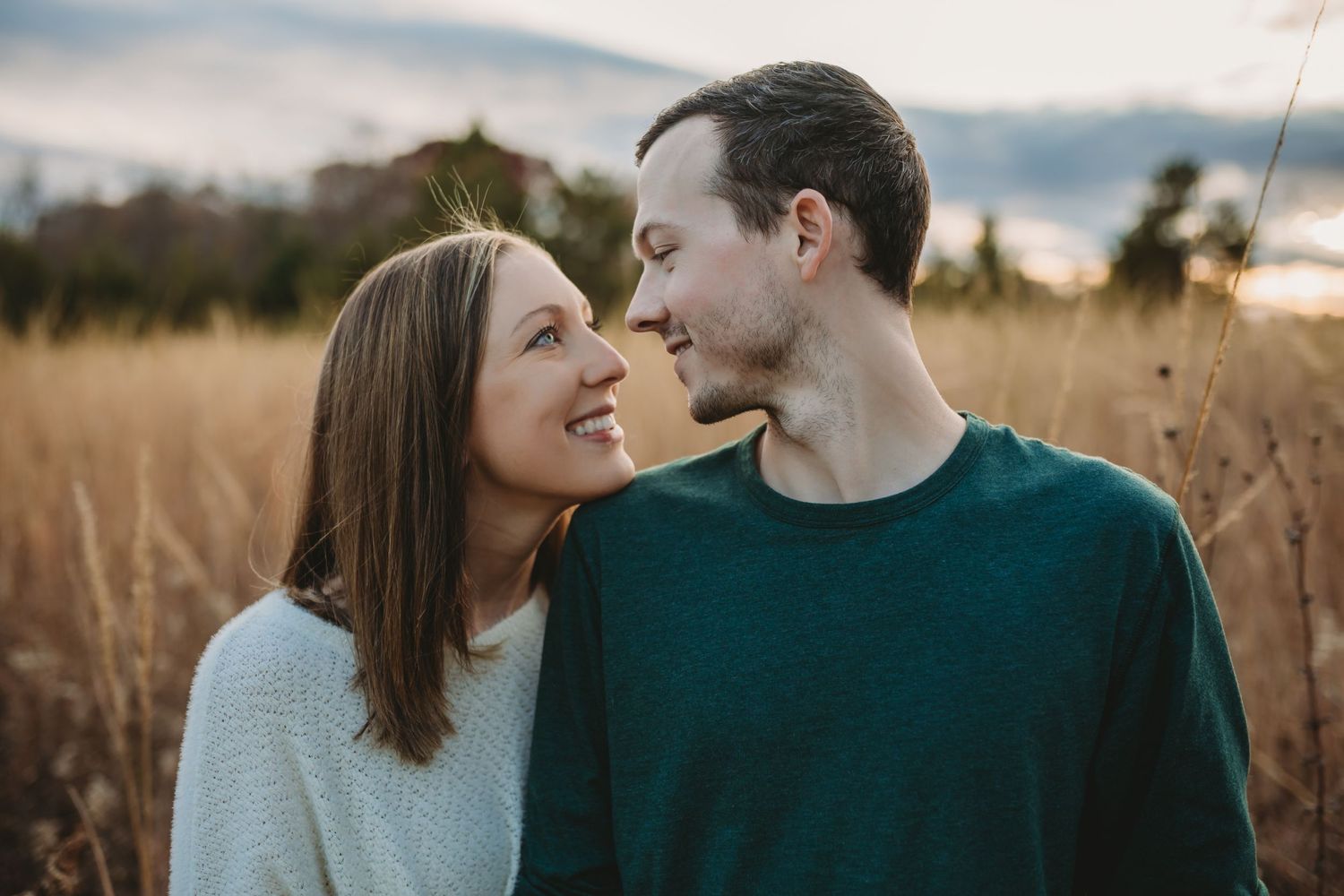 Couple in grassy field looking at each other smiling