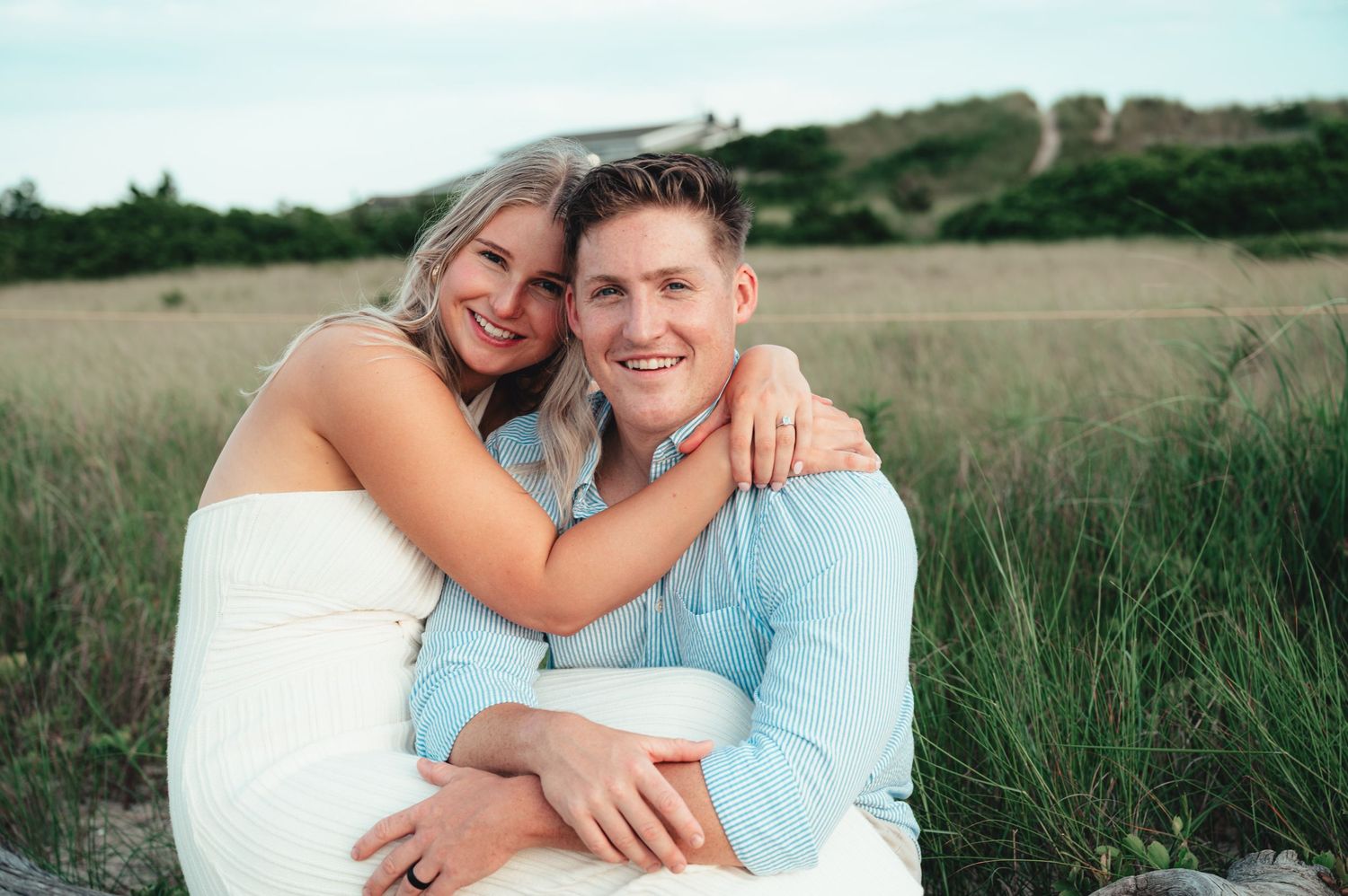 Couple poses for romantic engagement photos in coastal setting during golden hour.