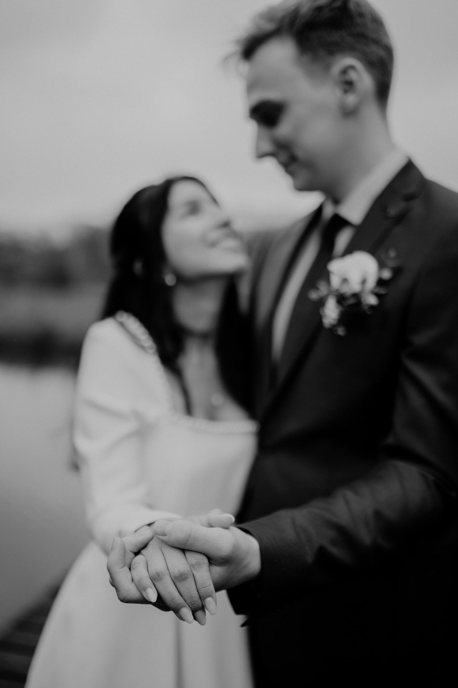 Black and white romantic wedding photograph showing close-up of couple holding hands with boutonniere detail in Hamburg Eppendorf.
