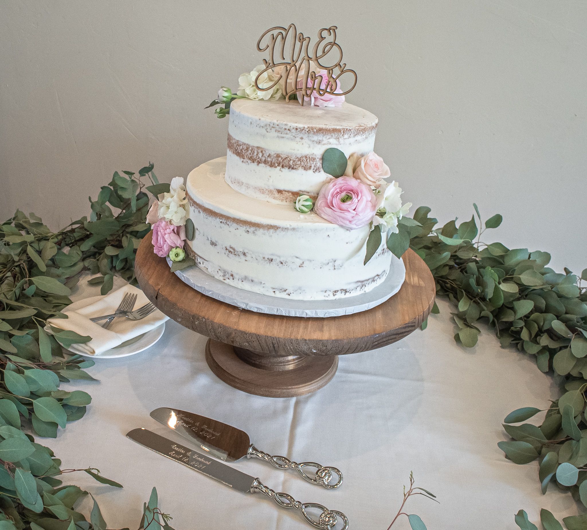 wedding cake topper says Mr. & Mrs. with fresh flowers on round table in wedding venue Gilroy, Ca