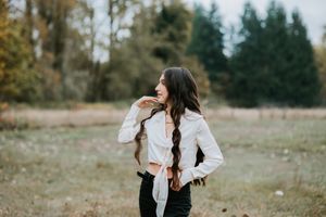 Casual outdoor autumn portrait with long braided hair and white button-down shirt.