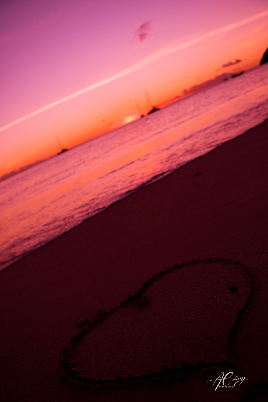 Dramatic pink and orange sunset over a dark ocean horizon creating silhouettes against the colorful sky.