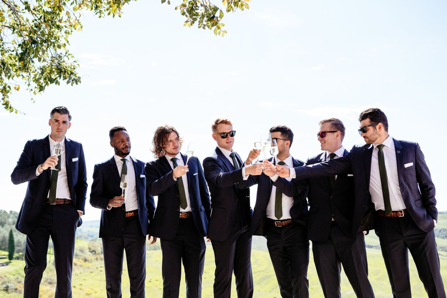 Groom and groomsmen toast with glasses of Prosecco before the wedding ceremony at the Lazy Olive Tuscany.