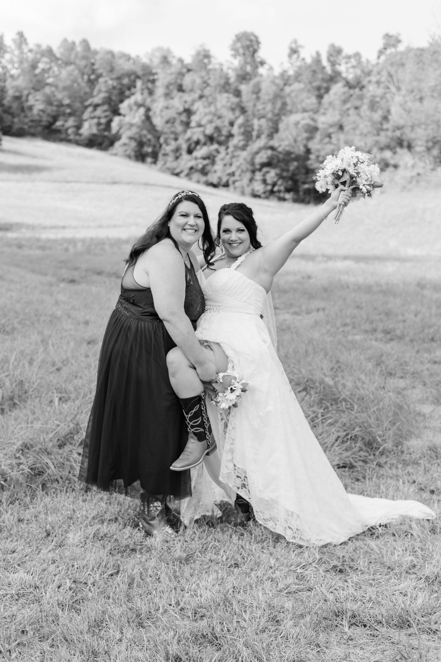 Black and white wedding photo showing joyful pose in a scenic field setting.