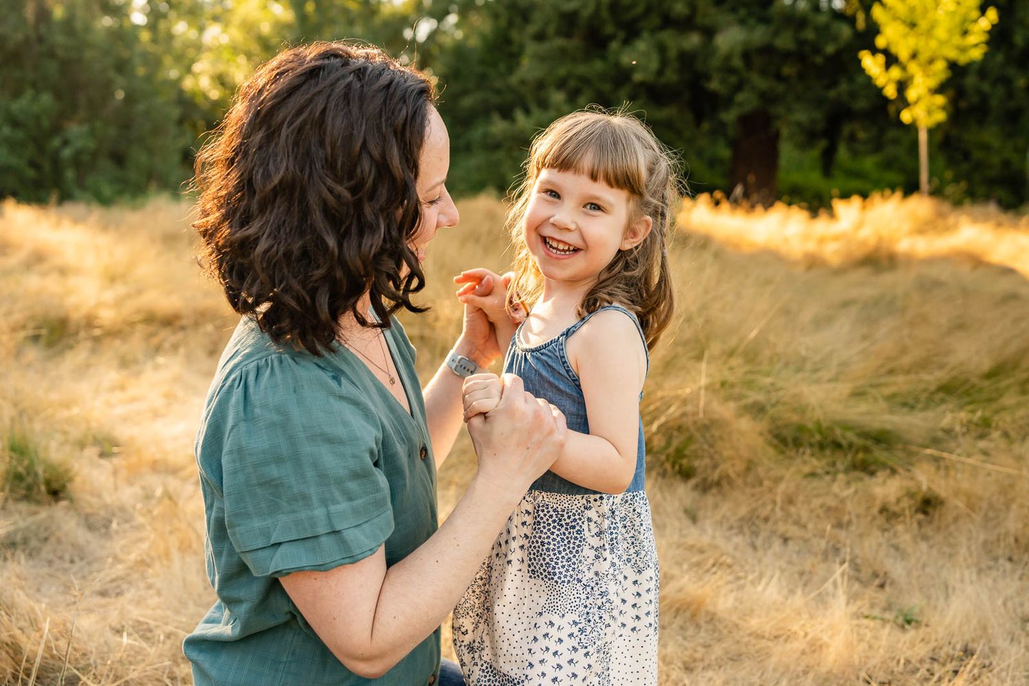Mother daughter smiling and holding hands in Juanita Bay Park.