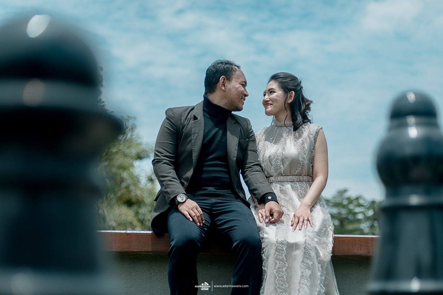 A couple shares an intimate moment sitting on a bench outdoors.