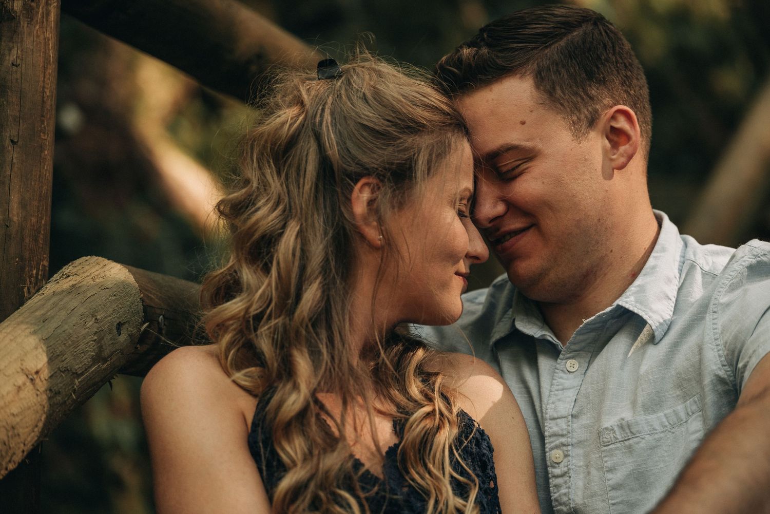 An intimate couples portrait captured on a rustic wooden bridge in the forest.