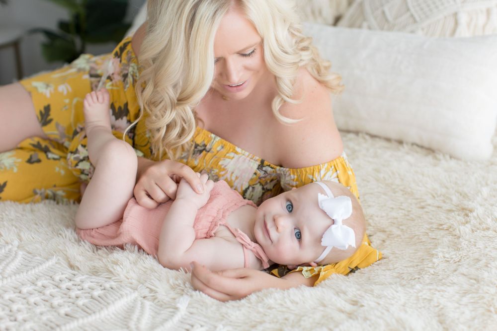 Professional portrait of tender moment on white bedding with yellow floral dress.