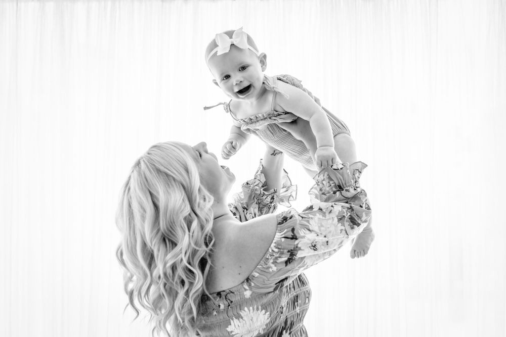 A joyful black and white portrait showing playful interaction between parent and baby.