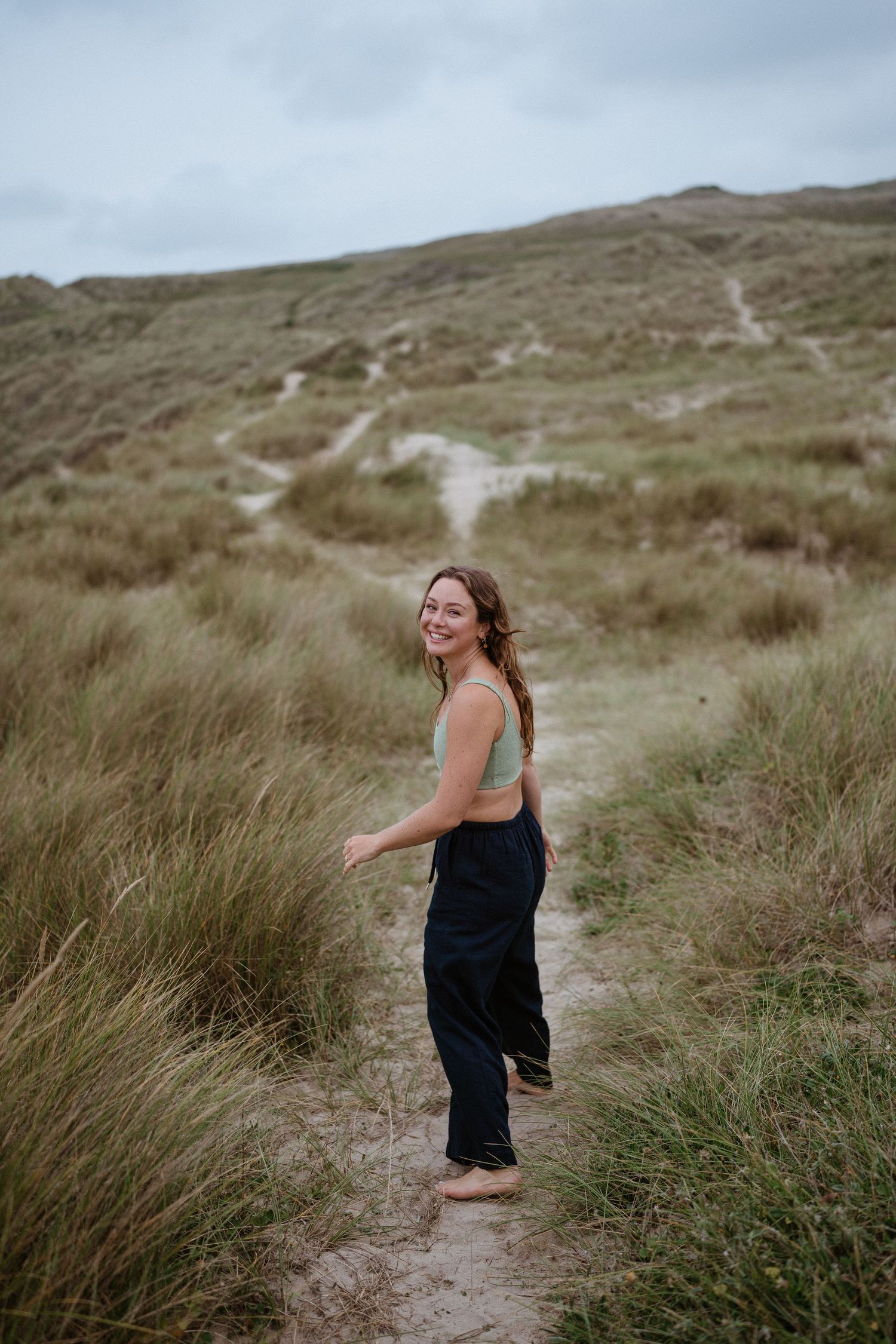 Joyful moment captured on hiking trail through windswept coastal grasslands.