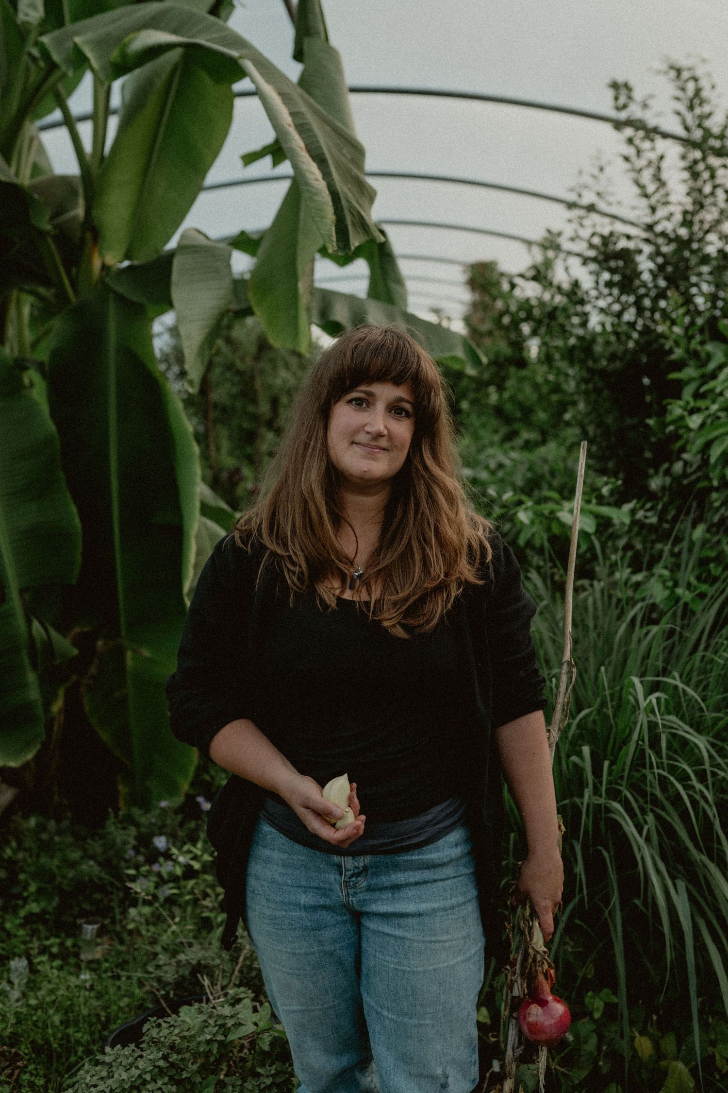 Person standing in a lush garden with banana plants and greenery.