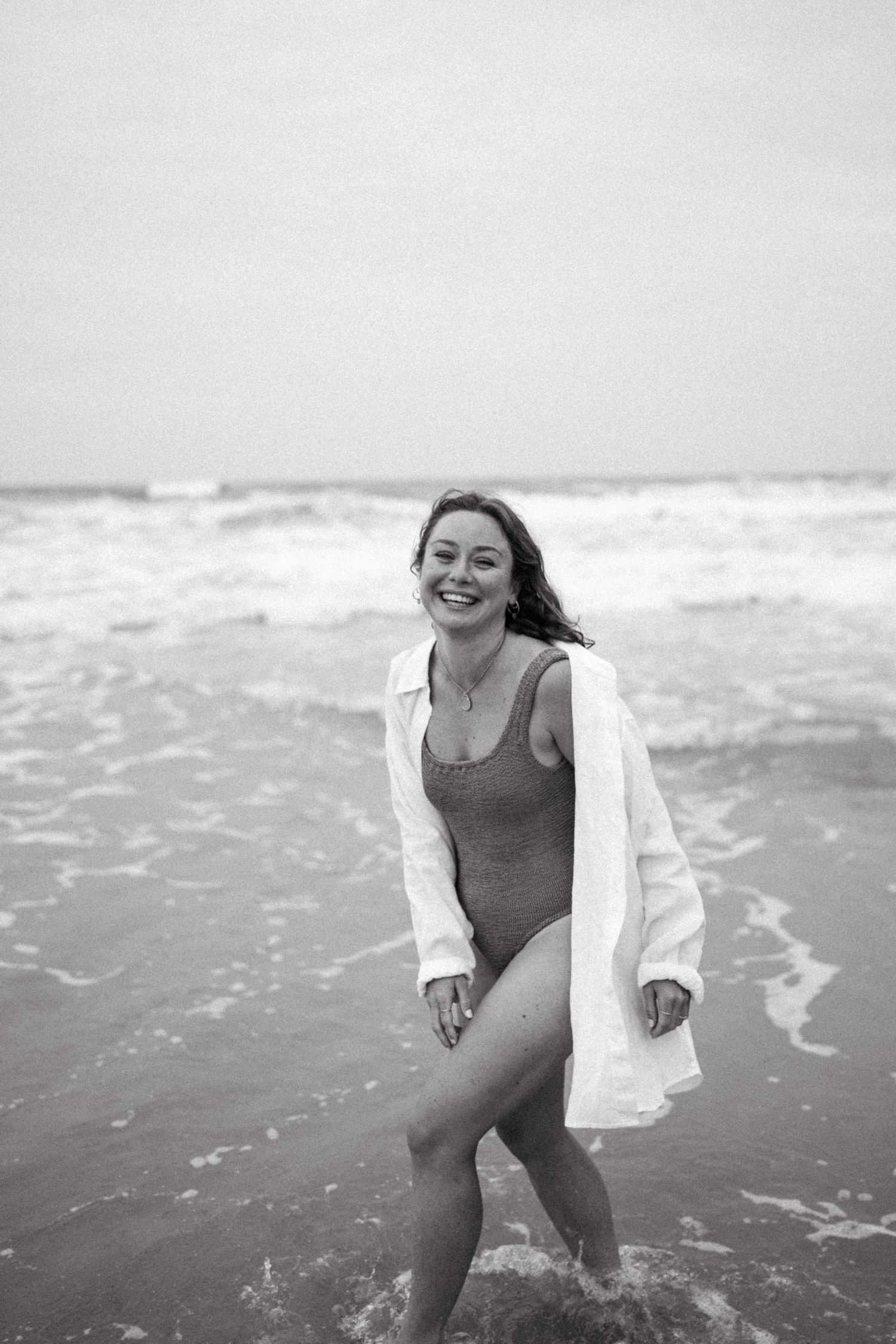 Black and white beach scene capturing carefree joy by the ocean waves.